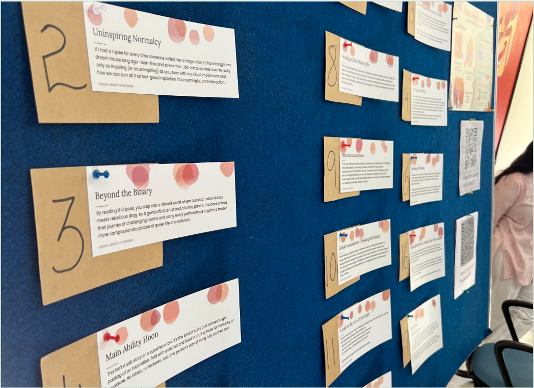 Living Book profiles pinned to a blue display board at an event.